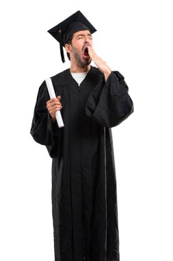 Esneme ve el ile geniş açık ağız kapsayan onun mezuniyet günü üniversite adamı. Uykulu ifade