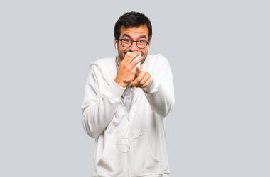 Adam gözlük ve biri parmak ile işaret ve çok ağız gri arka plan üzerinde kapsayan süre gülüyor müzik dinleme