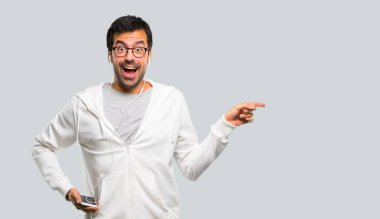 Adam gözlük ve parmak tarafına işaret ve kendinden emin bir poz gri arka plan üzerinde gülümseyen yaparken bir ürün sunma müzik dinleme