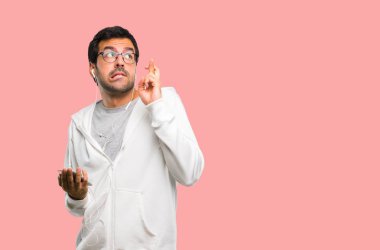 Adam gözlük ve en iyi dilek ve geçiş parmak ile müzik dinleme. Bir dilek yapma. pembe arka plan