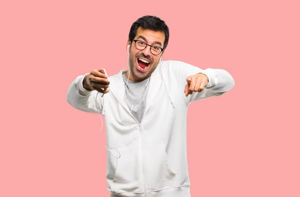 Człowiek Okulary Słuchania Muzyki Wskazując Palcem Kogoś Dużo Śmiechu Różowym — Zdjęcie stockowe