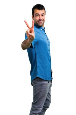 Gülümseyen ve zafer işaret gösteren mavi gömlek ile yakışıklı adam