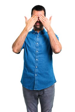 Gözleri eller tarafından kapsayan mavi gömlek ile yakışıklı adam