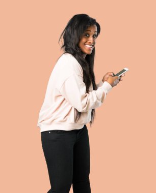 Genç afro Amerikalı kadın izole kahverengi zemin üzerinde mobil ileti gönderme