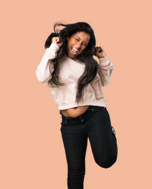 Genç afro Amerikalı kadın mutlu ve izole kahverengi zemin üzerine atlama