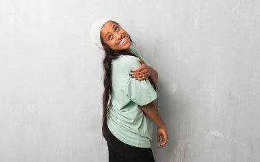 Bir gülümseme ile omuz üzerinden seyir dokulu arka plan üzerinde genç afro Amerikalı kadın