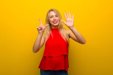 Yedi parmak ile sayma sarı duvarın üzerinden kırmızı elbise ile genç kız