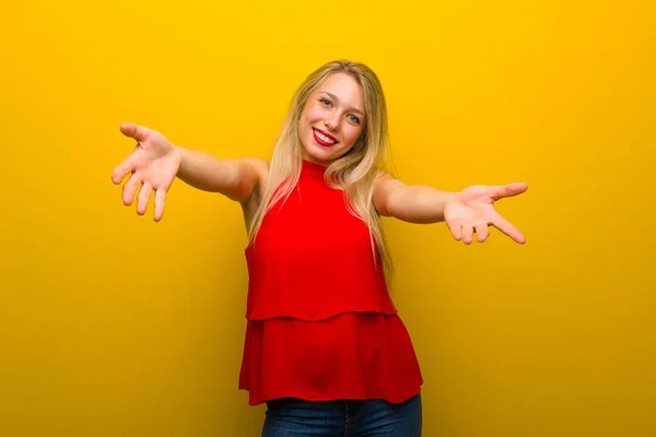 Młoda Dziewczyna Czerwoną Sukienkę Żółte Ściany Prezentując Zapraszając Wyposażone Ręcznie — Zdjęcie stockowe