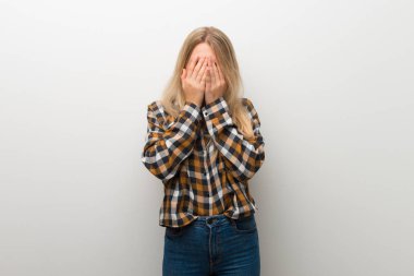 Sarışın genç kız yorgun ve hasta ifade ile beyaz duvar üzerinde