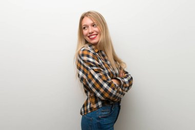 Sarışın genç kız beyaz duvar bir gülümseme ile omuz üzerinden seyir üzerinde