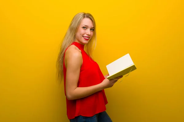 Rapariga Com Vestido Vermelho Sobre Parede Amarela Segurando Livro Gostando — Fotografia de Stock