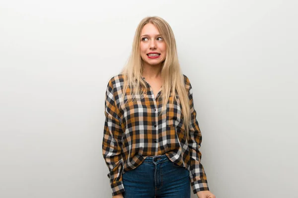 Loira Jovem Sobre Parede Branca Pouco Nervosa Assustada Pressionando Dentes — Fotografia de Stock