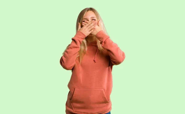 Mladá Dívka Pokrývající Ústa Rukama Říkám Něco Nepatřičného Zeleném Pozadí — Stock fotografie