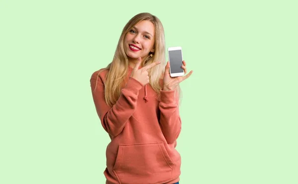 Junges Mädchen Zeigt Das Handy Auf Grünem Hintergrund — Stockfoto