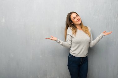 Genç kadın dokulu duvar omuz kaldırma sırasında önemli jest yapma