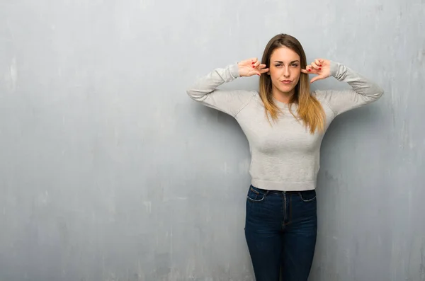 Mladá Žena Strukturované Stěny Pokrývá Obě Uši Rukama — Stock fotografie