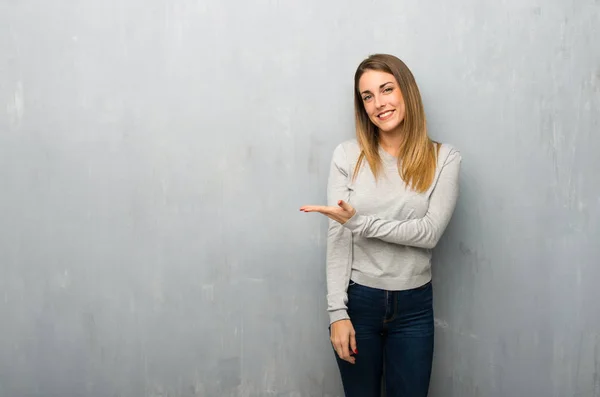 Jovem Mulher Parede Texturizada Apresentando Uma Ideia Enquanto Olha Sorrindo — Fotografia de Stock