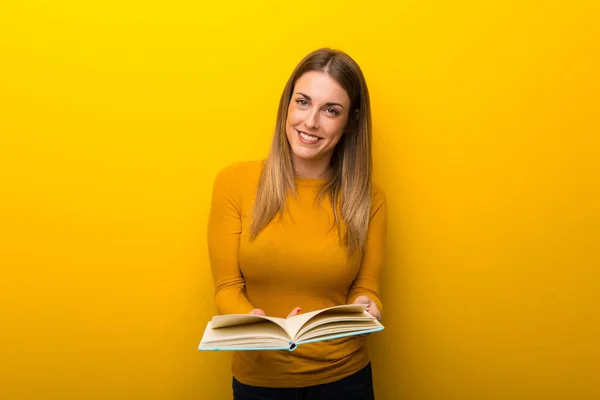 Junge Frau Auf Gelbem Hintergrund Hält Ein Buch Der Hand — Stockfoto