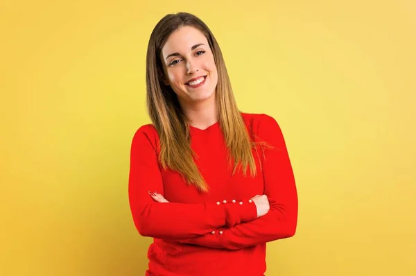 黄色の背景に 腕組みを保つ若いブロンドの女性 — ストック写真