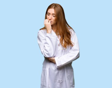 Kızıl saçlı doktor kadın izole mavi zemin üzerine şüpheleri