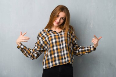 Grunge duvar gurur ve halinden memnun içinde genç Kızıl saçlı kız kendini kavram seviyorum