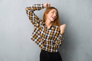 Genç Kızıl saçlı kız bir zaferini kutluyor grunge duvarın üzerinden