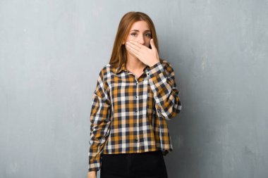 Uygunsuz bir şey söylediğin için el ile ağız kapsayan grunge duvarın üzerinden genç Kızıl saçlı kız