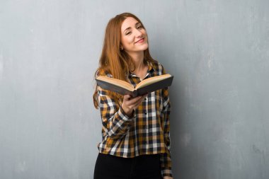 Bir kitap ve birine vererek grunge duvarın üzerinden genç Kızıl saçlı kız