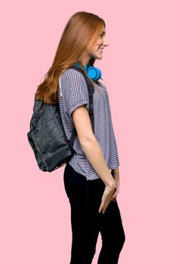 Kızıl saçlı öğrenci kadın lateral pozisyonda izole pembe arka plan