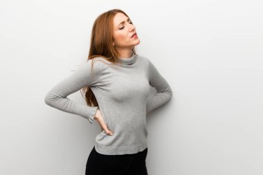 Kızıl saçlı kız beyaz duvar için bir çaba yapılmış olan sırt ağrısı muzdarip üzerinde