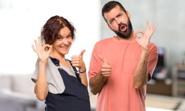 Ok işaret gösteren ve evin içinde jest diğer elinizle bir başparmak veren hamile kadın Çift