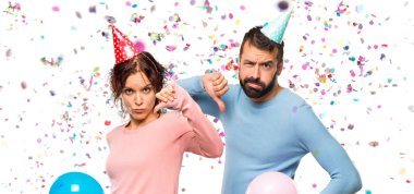 Balonlar ve bir parti başparmak aşağı konfeti ile negatif ifade işaretiyle gösterilen Doğum günü şapka ile çift
