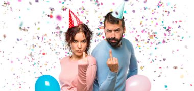 Balonlar ve boynuz jest yapma Doğum günü şapka ile bir çift gördüm. Konfeti bir parti ile negatif ifade