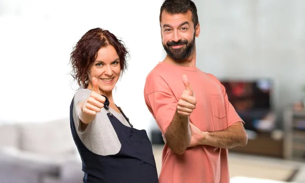 一对孕妇竖起大拇指的人在屋里微笑 — 图库照片