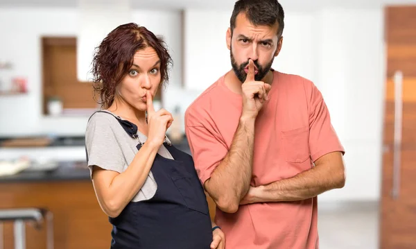 一对孕妇在屋内露出沉默手势的夫妇 把手指放在嘴里 — 图库照片