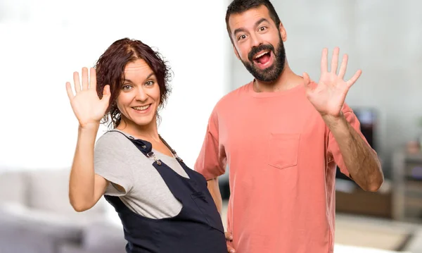 カップルは妊娠中の女性が家の中の幸せな表情で手で敬礼 — ストック写真