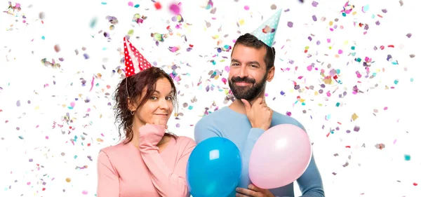 Paar Mit Luftballons Und Geburtstagsmützen Lächelt Und Blickt Nach Vorne — Stockfoto