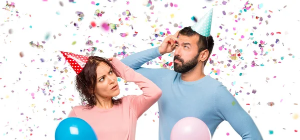 Casal Com Balões Chapéus Aniversário Com Dúvidas Com Rosto Confuso — Fotografia de Stock