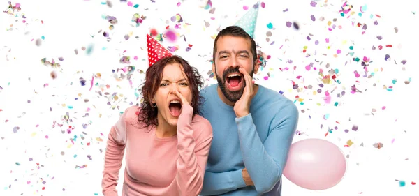 Paar Mit Luftballons Und Geburtstagsmützen Schreit Mit Weit Aufgerissenem Mund — Stockfoto