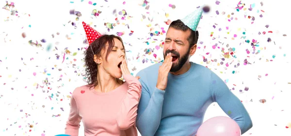 Pareja Con Globos Sombreros Cumpleaños Bostezando Cubriendo Boca Con Mano —  Fotos de Stock