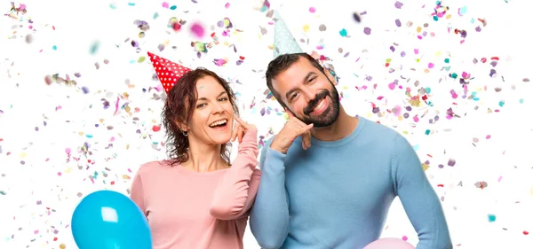 Pareja Con Globos Sombreros Cumpleaños Haciendo Gesto Telefónico Llámame Signo —  Fotos de Stock