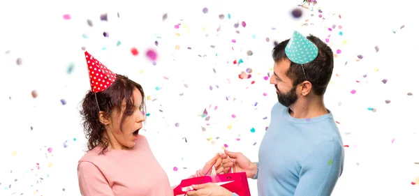 couple with birthday hats and with shopping bags with confetti in a party