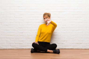 Başparmak aşağı negatif ifade işaretiyle gösterilen katta oturan genç kız