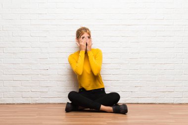 Gözleri eller tarafından kapsayan ve parmaklarının arasından seyir katta oturan genç kız