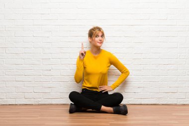 Gösteren ve en iyi iz içinde parmak kaldırma yerde oturan genç kız