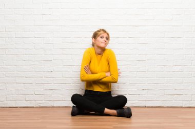 Açık kat yapma oturan genç kız omuz kaldırma sırasında jest şüpheler