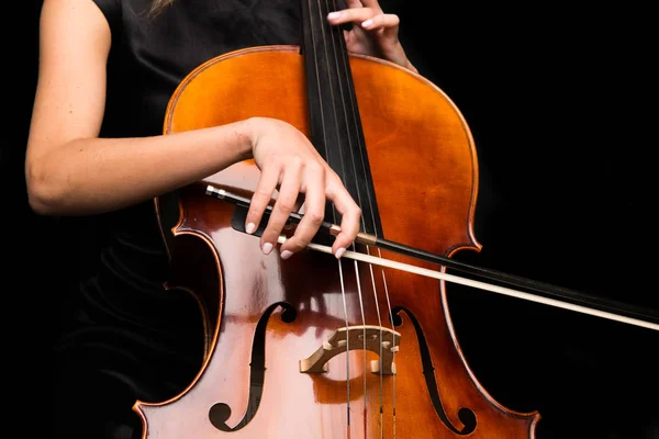 在孤立的黑色背景上演奏大提琴的年轻女孩 — 图库照片