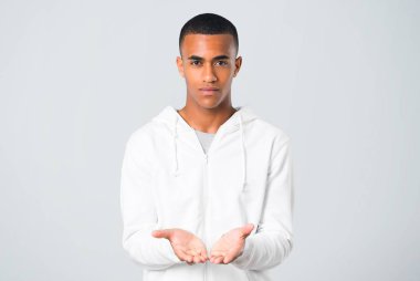 Gri arka plan üzerinde bir reklam eklemek için esmer genç adamla beyaz kazak boşaltmak hayali avuç içinde tutan