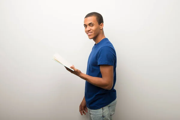本を持って 読書を楽しんでいる白い壁の若いアフリカ系アメリカ人 — ストック写真