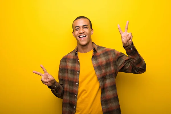 Mladý Americký Muž Zářivé Žluté Pozadí Úsměvem Vítězství Známek Oběma — Stock fotografie